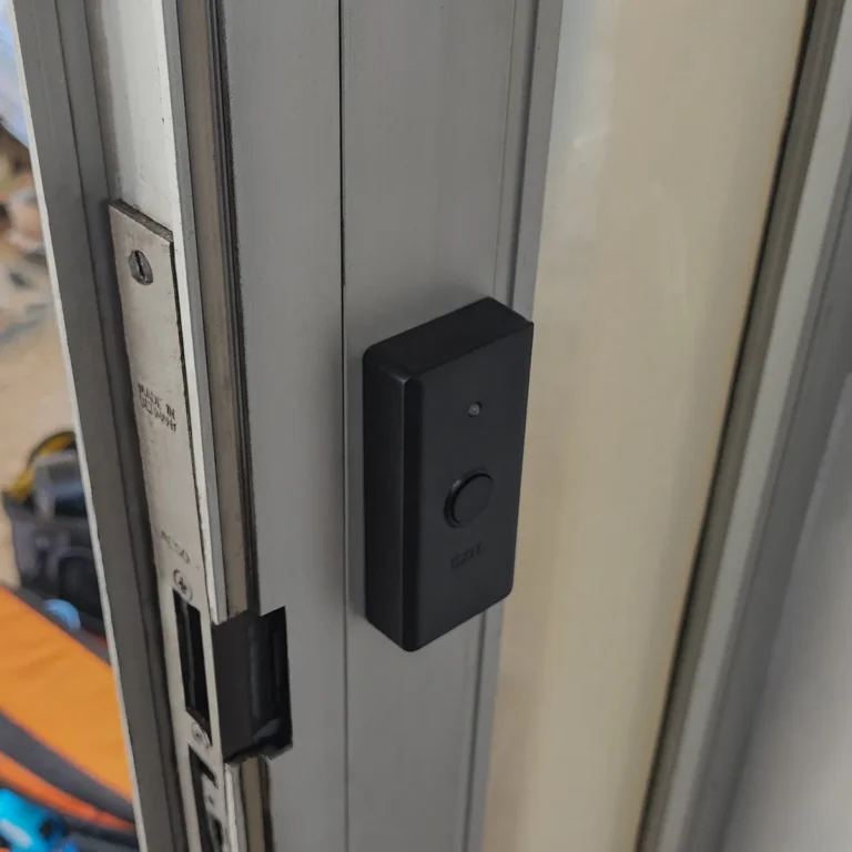 Ηλεκτρονικό κουμπί εξόδου Deltronlock εγκατεστημένο σε πόρτα πολυκατοικίας, για εύκολη και ασφαλή έξοδο.